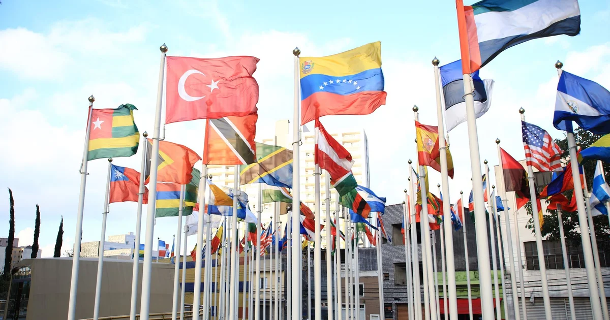 Banderas de varios países ondeando juntas al aire libre en una ciudad